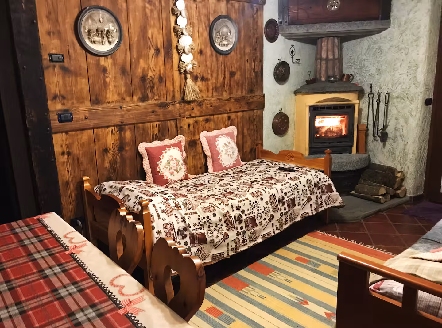 Cosy living area with rustic wooden sofa, glowing wood-burning stove and alpine wall panels